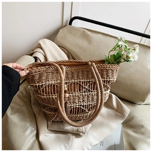 Detail of hollow-out straw tote bag featuring tassel wooden beads and fabric lining