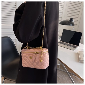 Detailed view of pink quilted PU leather vanity bag with gold floral clasp and chain strap