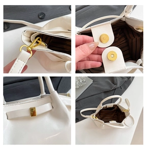 Detail view of white PU leather bag showing gold hardware, magnetic buckle and striped lining