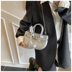Detail of silver metallic shell bag with heart applique and classic buckle strap