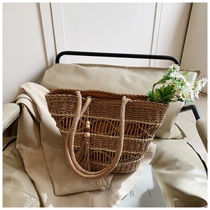 Detailed close-up of woven straw tote bag with boho tassel and wooden beads decor