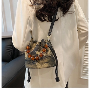 Detail of embroidered butterfly bucket bag with amber beads and drawstring tassel
