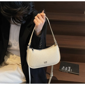 Detail shot of cream shoulder bag with textured embossing and metal logo detail