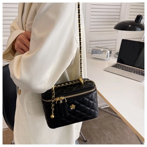 Detail view of black quilted leather box bag with gold floral clasp and chain strap