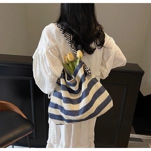 Détail du sac cabas tissé à rayures bleues et blanches avec bandoulière sur le modèle