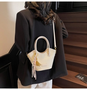 Detailed back view of white woven textured bucket bag with elegant tassel and gold charms