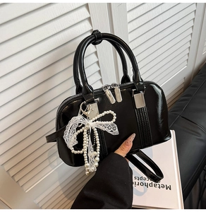 Detailaufnahme einer glänzenden schwarzen Boston-Handtasche mit Perlen-Spitzenbogen