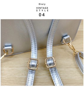 Detail of silver leather backpack strap with gold metal buckle on wood background