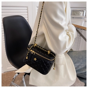 Close-up of quilted leather bucket bag with golden camellia charm and woven chain strap