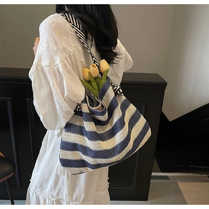 Détail du sac cabas tissé à rayures bleues et blanches avec silhouette hobo et bandoulière