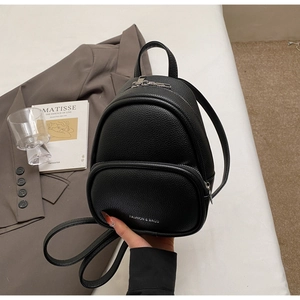 Close-up of black litchi grain leather mini backpack featuring white fashion text logo