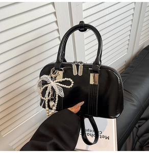 Detailansicht der schwarzen Lacktasche mit Perlen-Schleife und Spitzenverzierung