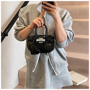 Detail of glossy black patent leather mini bag with silver clasp and heart charm