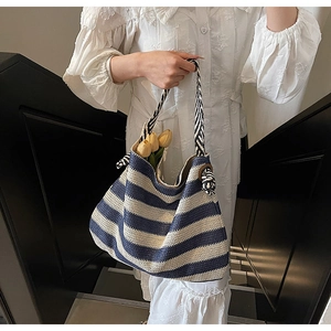 Détail d'un sac cabas tissé à rayures bleues et beiges avec poignées en anneaux de bois