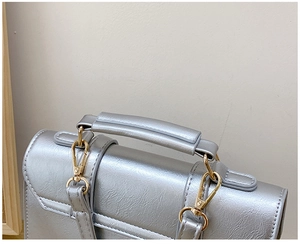 Detail of silver metallic tote bag featuring thickened handles and gold metal swivel hooks