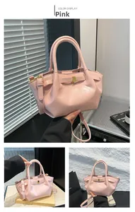 Detail view of pink glossy PU leather motorcycle bag with gold buckle bow accent