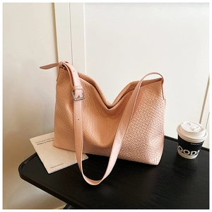 Detailed view of pink woven tote bag showing leather texture and adjustable buckle strap