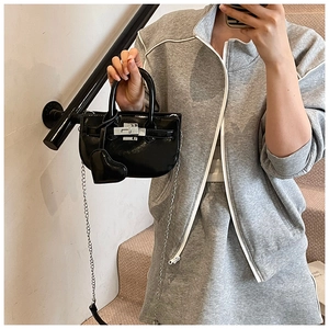 Close-up of black glossy shell bag featuring silver turn-lock and elegant heart charm