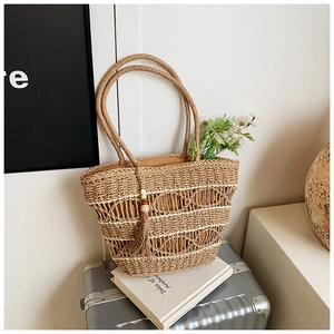 Detailed close-up of woven straw bag texture with decorative wooden bead tassel and lining