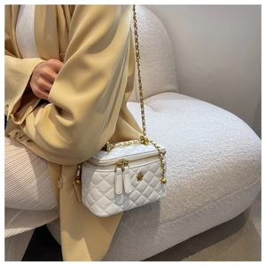 Detail of white quilted leather bucket bag with gold chain strap and floral accent