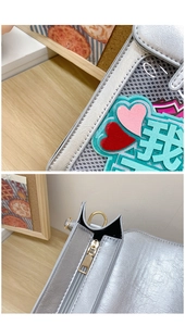 Macro view of silver metallic handbag detailing colorful heart patches and gold zippers