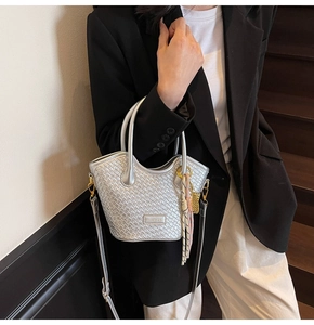Detail of silver woven handbag with metallic texture, decorative scarf, and brand logo