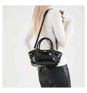 Détail du sac en cuir PU noir brillant avec ouverture plissée et boucle dorée