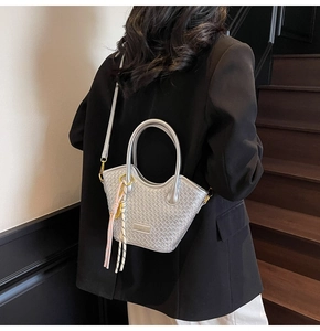 Silver woven crossbody bag with metallic finish and tassel charm on a model