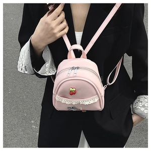 Detail van roze mini-rugzak met kant, kersenhanger en geruite strik voor meisjes