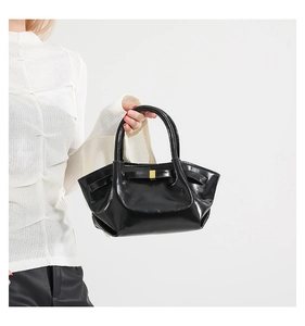 Détail d'un sac moto noir brillant en similicuir avec une boucle dorée élégante