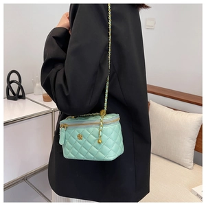 Detail of mint green quilted crossbody bag with gold chain strap on a model outfit