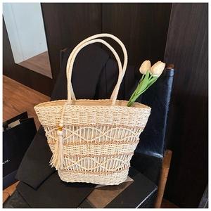 Detail of bohemian hollow straw tote bag featuring intricate weave and tassel charm