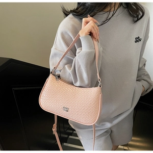 Detail of light pink woven leather shoulder bag with silver hardware on model