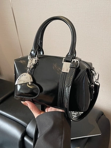 Glossy black bowling bag with silver hardware and heart pendant on a clean background