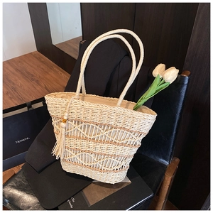 Detail of hand-woven straw tote with diamond patterns and chic tassel charm on a chair