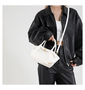 Close-up of white high-gloss PU leather handbag featuring pleated folds and gold hardware
