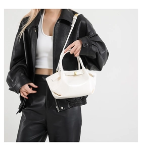 Détail du sac blanc en similicuir à nœud porté sur une veste en cuir noir