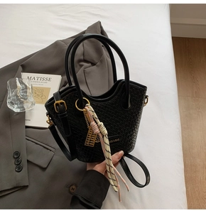 Detailed shot of black woven handbag featuring golden abacus charm and colorful rope