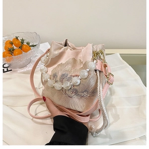 Close-up of pink silk bucket bag with flower embroidery and elegant pearl handle
