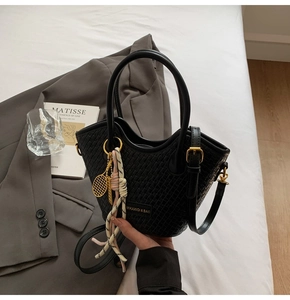 Close-up of black woven bucket bag with tennis racket charm and colorful knot tassels