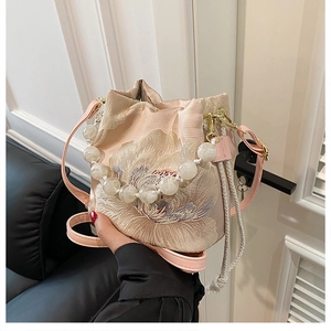 Detail of light pink bucket bag with floral embroidery and white pearl handle