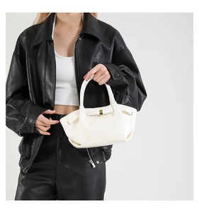 Detail view of white oil wax leather bucket bag with pleats and gold buckle