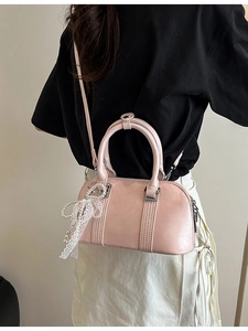 Rosa Boston-Handtasche mit Perlen-Spitzenanhänger und Schultergurt an einem Damenmodell