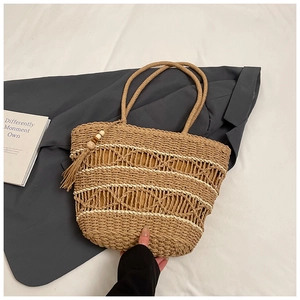 Detailed straw tote bag with intricate hollow weave and tassel with wooden beads