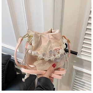 Close-up of pink satin bucket bag with floral embroidery and pearl beaded handle