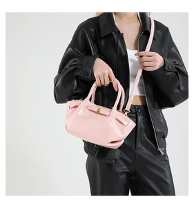 Detail of pink faux leather crossbody bag with bow accent and metallic hardware