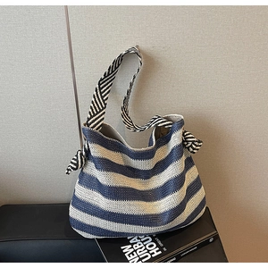 Détail de la texture tissée à rayures bleues et blanches et nœud décoratif du sac