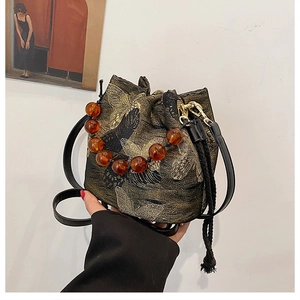 Detailed texture of butterfly jacquard fabric and amber bead handle on bucket bag