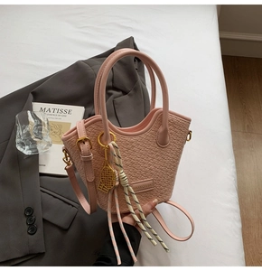 Detail of woven texture on pink crossbody bucket bag with tennis racket charm