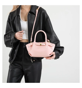 Détail du sac à main en cuir verni rose avec boucle nœud et bandoulière amovible